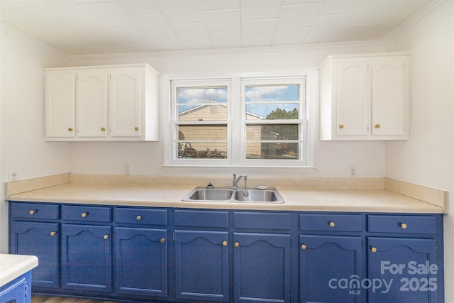 kitchen featuring light countertops, blue cabinetry, a sink, and white cabinets