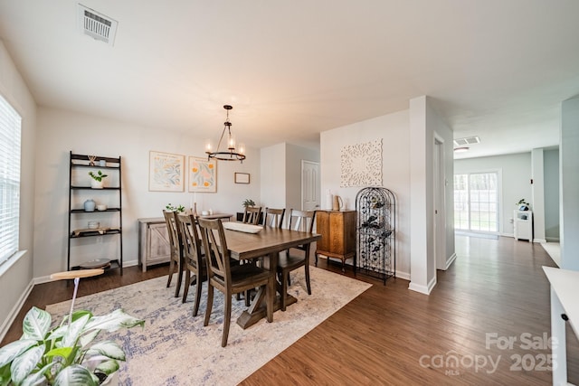 dining area with a notable chandelier, baseboards, visible vents, and dark wood-type flooring