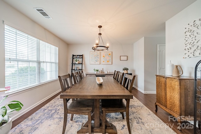 dining room featuring a chandelier, dark wood finished floors, visible vents, and baseboards