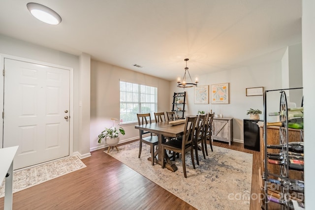 dining room featuring baseboards, visible vents, a chandelier, and wood finished floors