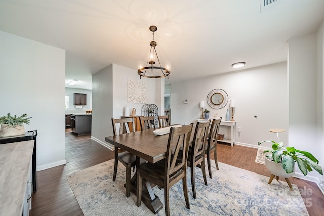 dining room with a notable chandelier, baseboards, and dark wood-style flooring