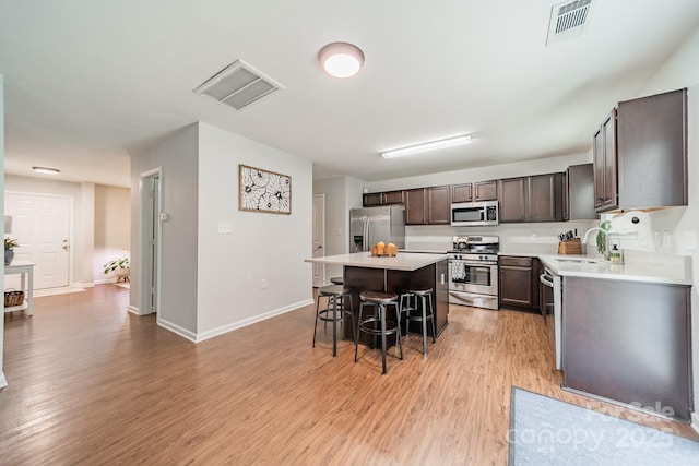 kitchen featuring a breakfast bar area, light wood-style flooring, visible vents, appliances with stainless steel finishes, and a center island