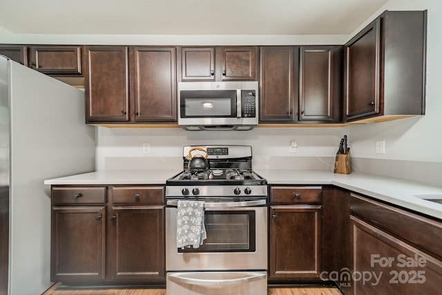 kitchen featuring dark brown cabinetry, appliances with stainless steel finishes, and light countertops