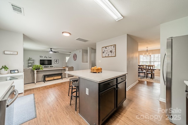 kitchen featuring light wood-style flooring, visible vents, open floor plan, freestanding refrigerator, and a kitchen bar