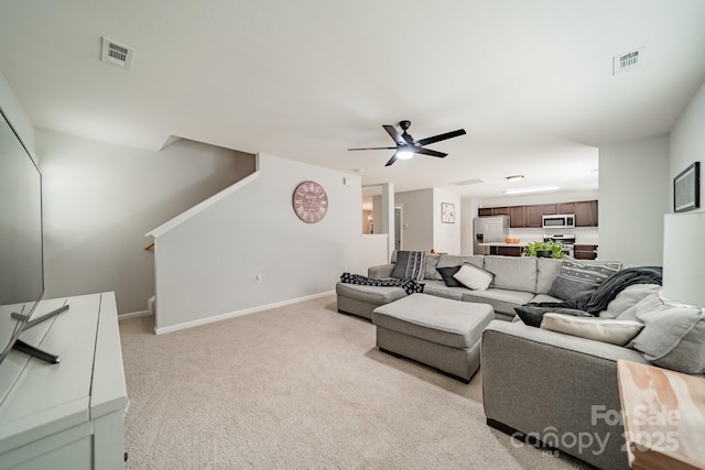 living room with visible vents, ceiling fan, light carpet, and baseboards