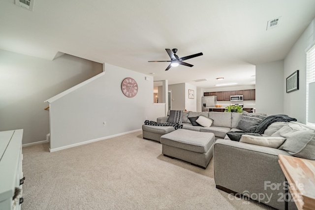 living room featuring visible vents, baseboards, ceiling fan, and light colored carpet