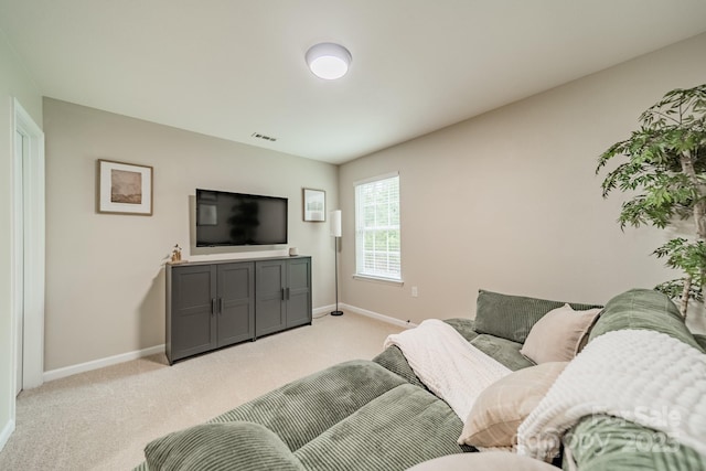 living area featuring baseboards, visible vents, and light colored carpet