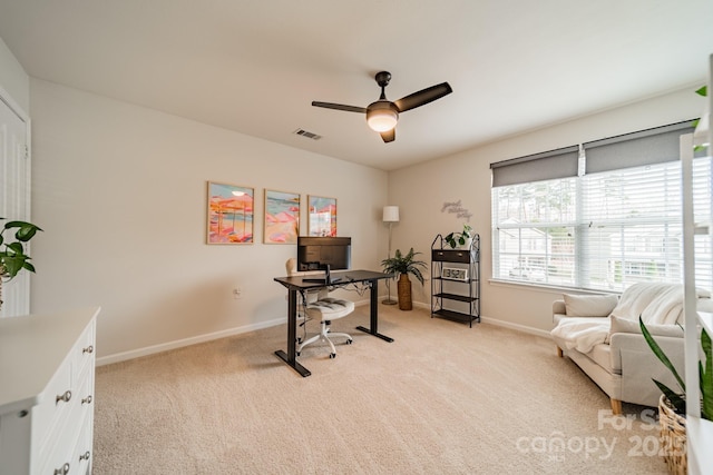 office area featuring a ceiling fan, light colored carpet, visible vents, and baseboards