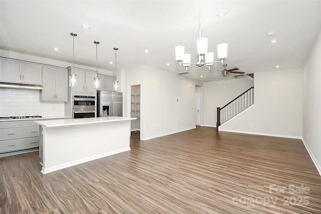 kitchen with stainless steel appliances, gray cabinets, light countertops, and wood finished floors