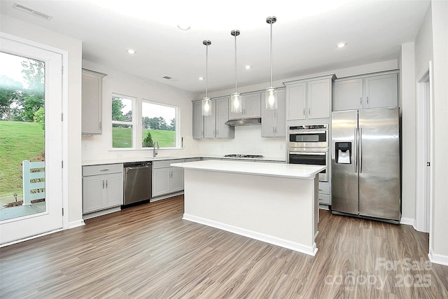 kitchen with visible vents, stainless steel appliances, light countertops, gray cabinetry, and under cabinet range hood