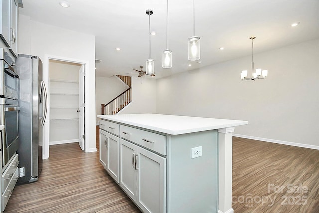 kitchen featuring recessed lighting, light countertops, appliances with stainless steel finishes, a center island, and dark wood-style floors