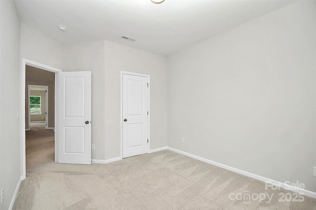 unfurnished bedroom with visible vents, baseboards, and light colored carpet