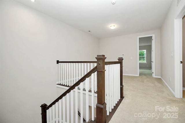 corridor featuring light carpet, an upstairs landing, and baseboards