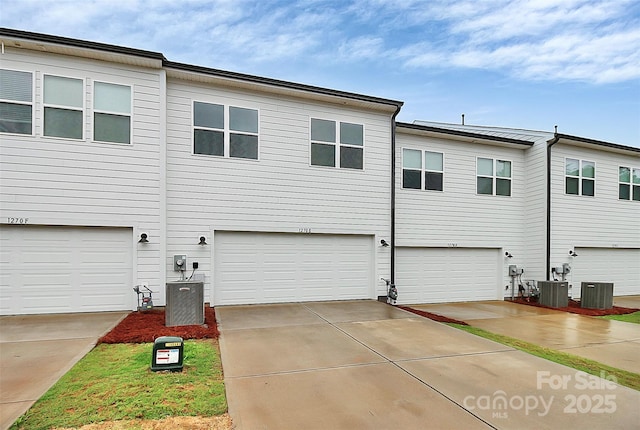 view of front of house featuring a garage, central AC unit, and concrete driveway