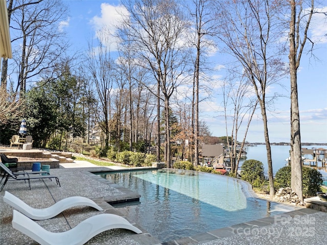 outdoor pool featuring a water view and a patio area