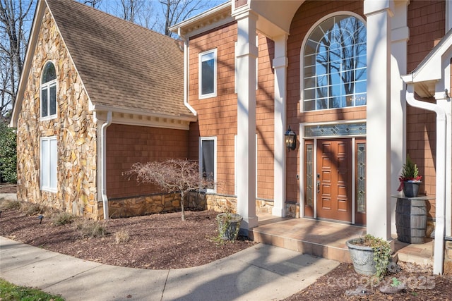 property entrance with stone siding and roof with shingles