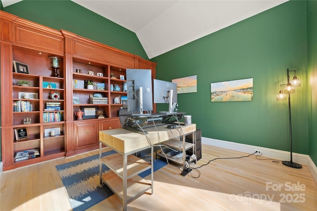 office area featuring lofted ceiling, baseboards, and light wood finished floors