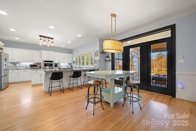 dining space featuring recessed lighting, light wood-style flooring, and crown molding
