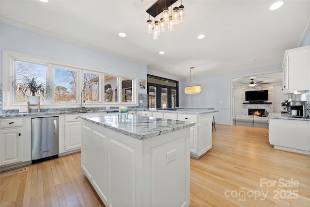 kitchen featuring refrigerator, a center island, a fireplace, and white cabinetry