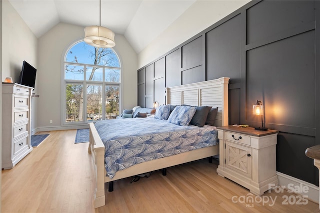 bedroom featuring light wood finished floors and high vaulted ceiling