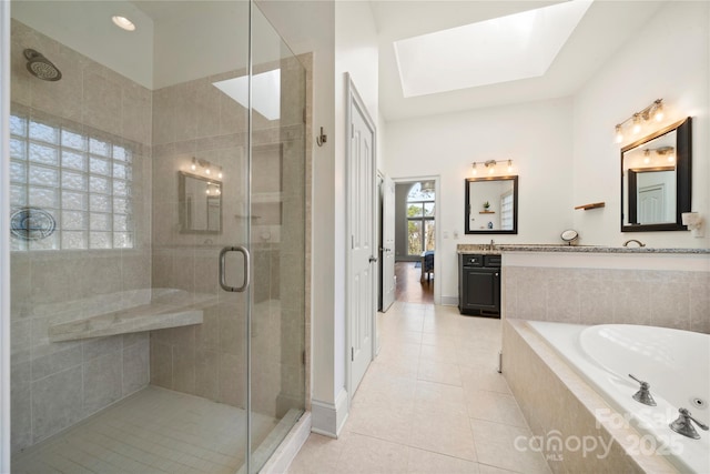 full bath featuring a garden tub, a stall shower, a skylight, tile patterned flooring, and vanity