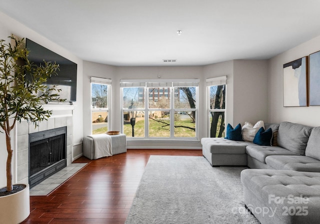 living area featuring visible vents, wood finished floors, and a fireplace