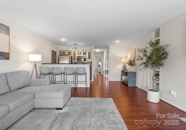 unfurnished living room with recessed lighting, baseboards, an inviting chandelier, and wood finished floors