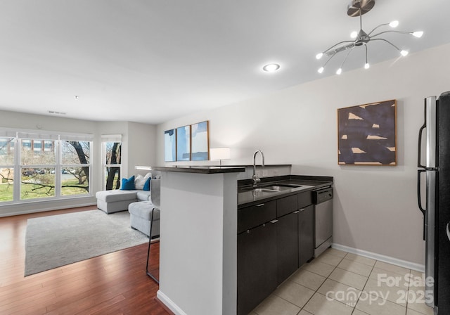 kitchen with a peninsula, freestanding refrigerator, a sink, dishwasher, and open floor plan