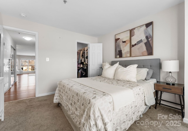 carpeted bedroom featuring baseboards and a spacious closet