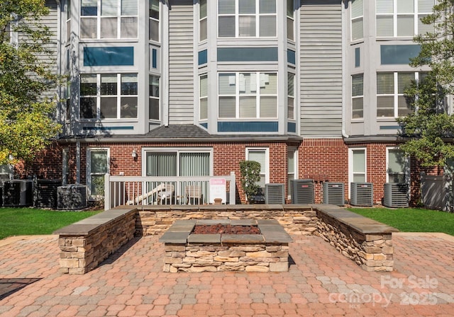 back of property featuring central air condition unit and brick siding