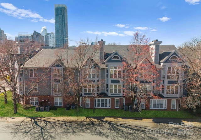 view of front of property featuring a view of city, brick siding, central AC unit, and a front yard