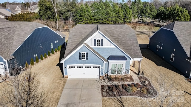 view of front of home with roof with shingles, board and batten siding, a standing seam roof, a garage, and driveway