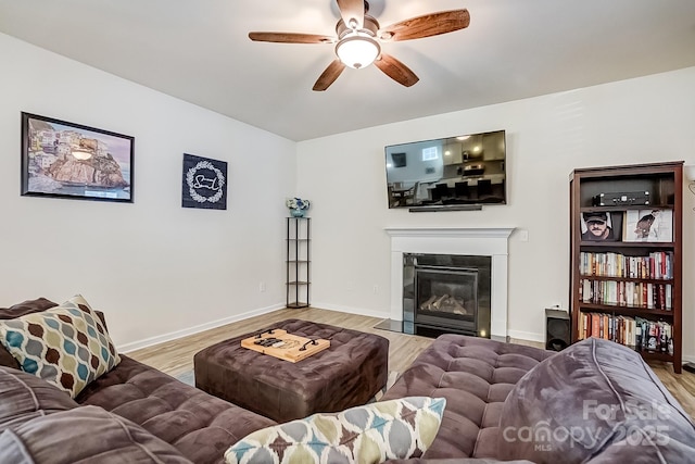 living room with ceiling fan, wood finished floors, a fireplace with flush hearth, and baseboards