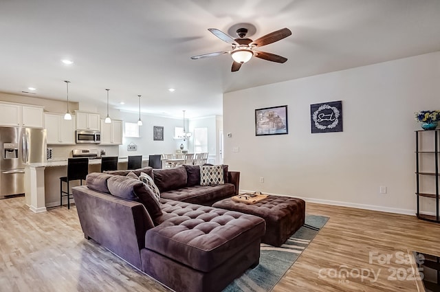 living room featuring a ceiling fan, light wood-type flooring, baseboards, and recessed lighting