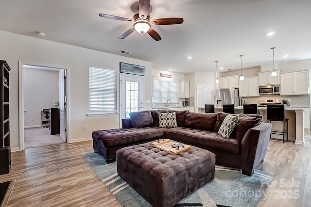 living room featuring light wood finished floors, baseboards, visible vents, and recessed lighting