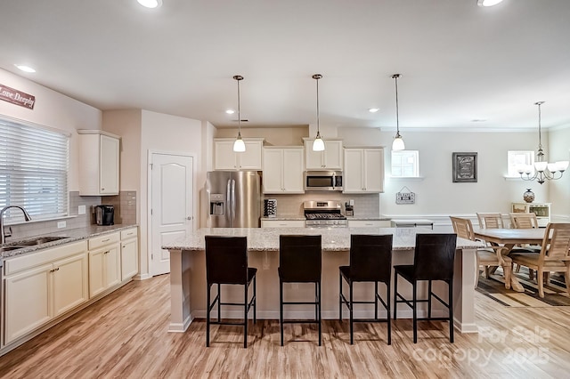 kitchen with appliances with stainless steel finishes, a sink, light wood-style floors, and a center island