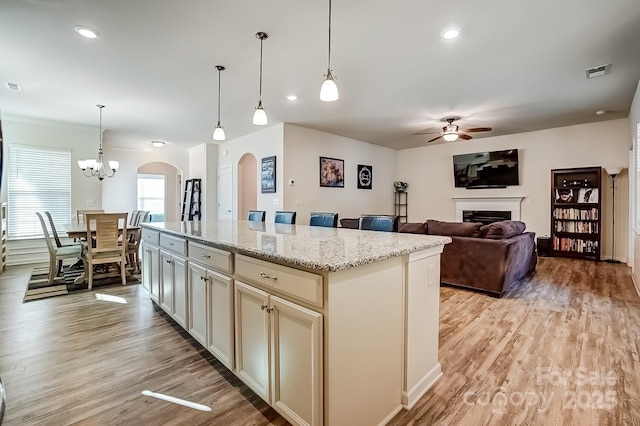 kitchen featuring light wood-style floors, arched walkways, visible vents, and a fireplace