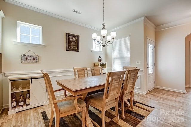 dining room with a notable chandelier, visible vents, baseboards, ornamental molding, and light wood-type flooring