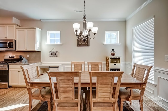 dining room featuring light wood finished floors, visible vents, crown molding, and an inviting chandelier