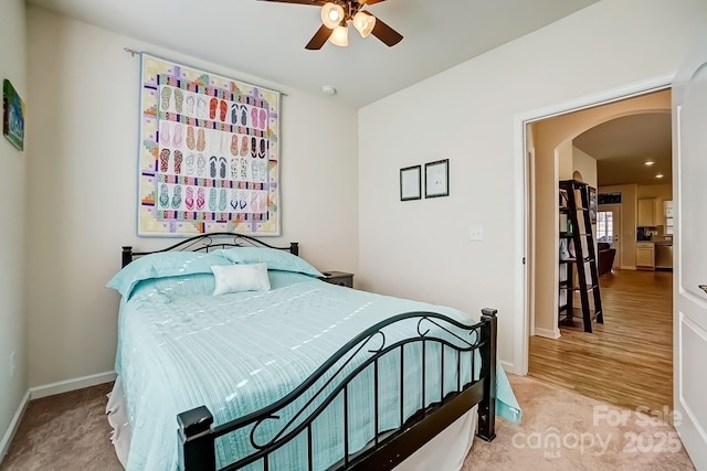 bedroom with a ceiling fan, arched walkways, and baseboards