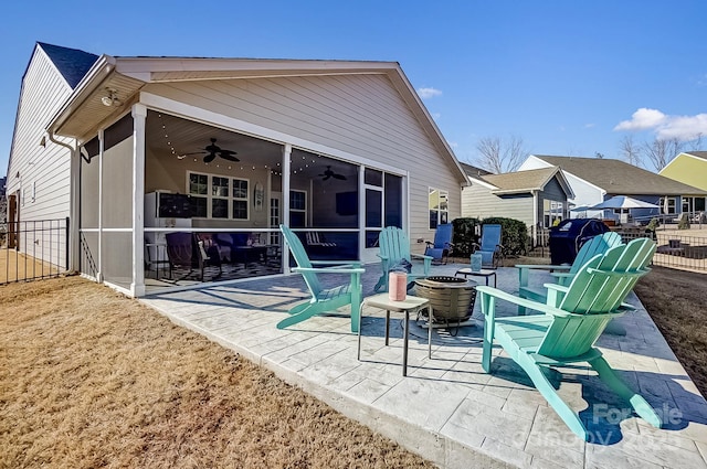 back of house with an outdoor fire pit, a sunroom, ceiling fan, fence, and a patio area