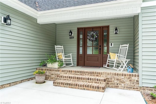 entrance to property featuring a shingled roof and a porch