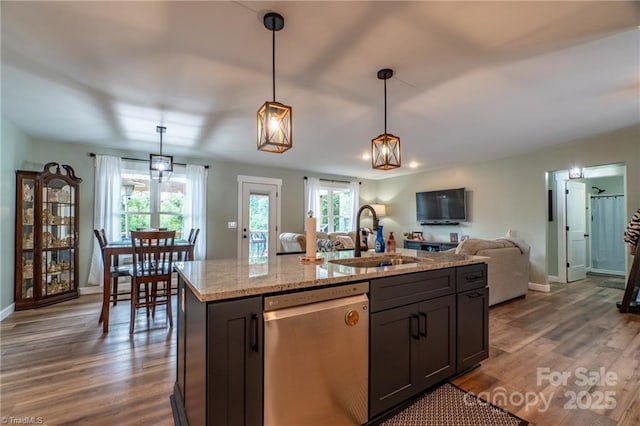 kitchen with pendant lighting, dark wood-style flooring, open floor plan, a sink, and dishwasher