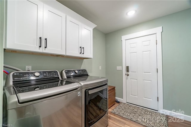 laundry room featuring light wood-style flooring, washing machine and clothes dryer, cabinet space, and baseboards