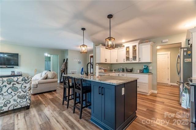 kitchen featuring light stone counters, light wood-style flooring, white cabinetry, open floor plan, and freestanding refrigerator