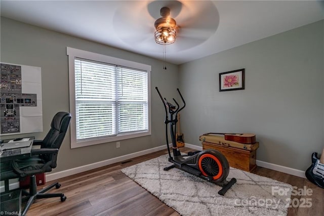 interior space featuring wood finished floors, a ceiling fan, and baseboards