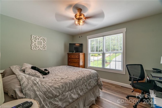 bedroom featuring a ceiling fan, baseboards, and wood finished floors