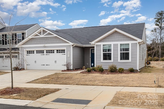 view of front facade with a shingled roof, concrete driveway, and an attached garage