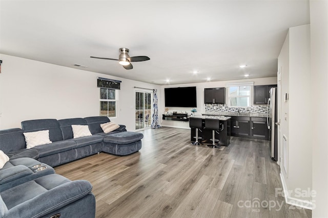 living room with a ceiling fan, recessed lighting, visible vents, and light wood-style flooring