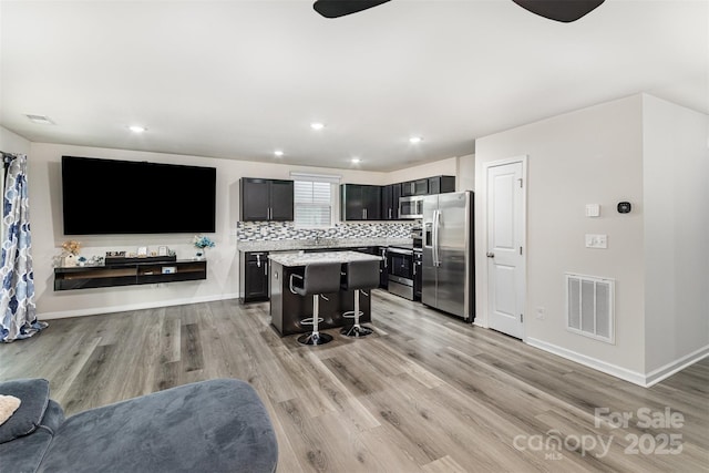 kitchen featuring visible vents, light wood-style flooring, a center island, stainless steel appliances, and light countertops